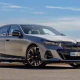 Srebrne BMW 520 z czarnymi akcentami stoi na tle błękitnego nieba i morza.