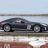 Elegancki, ciemnoszary Peugeot 907 sunie po drodze nad różowym jeziorem.