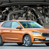 Pomarańczowa Skoda Fabia IV z widocznym silnikiem w tle.