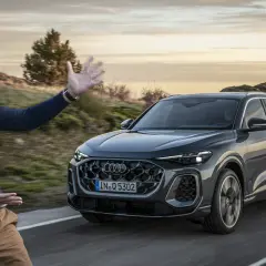Mężczyzna prezentuje Audi Q5, podkreślając jego imponujące audi q5 wymiary. Jazda po malowniczej drodze o zachodzie słońca.