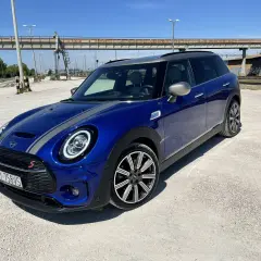 Niebieski Mini Cooper Clubman S z szarymi pasami na masce. Wiele osób chwali sobie jego zwinność i styl, co potwierdzają liczne mini cooper opinie.