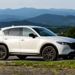 Biała Mazda CX-5 z czarnymi felgami na tle górskiego krajobrazu. KSU rejestracja widoczna na tablicy.