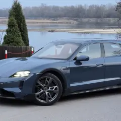 Niebieski Porsche Taycan Turbo S na tle rzeki i drzew.