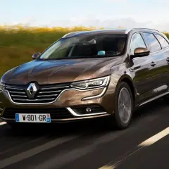 Brązowe kombi Renault Talisman na drodze. Wiele osób szuka renault talisman opinie przed zakupem.