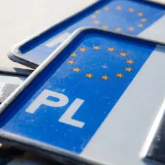 Zbliżenie na polskie tablice rejestracyjne z symbolem Unii Europejskiej. Widoczne litery "PL" i fragmenty numerów.