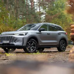 Srebrny SUV w lesie, gotowy na przygodę. Wiele pozytywnych baic 7 opinii potwierdza jego wszechstronność.