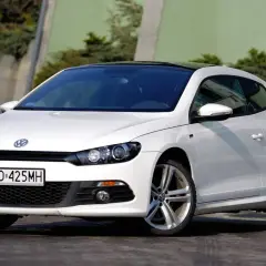 Biały Volkswagen Scirocco z czarnym dachem, zaparkowany na zewnątrz.