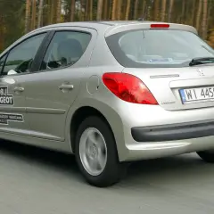 Srebrny Peugeot 207 1.4 benzyna w ruchu drogowym. Na drzwiach naklejka "Wypróbuj Peugeot".