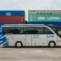 Autobus szkoleniowy z napisem "Linia Nauka Jazdy" na tle kontenerów. Sprawdź, jaka jest prawo jazdy kat d cena i zacznij kurs!