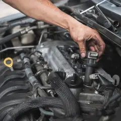 Mechanik wymienia cewki zapłonowe w silniku samochodu.