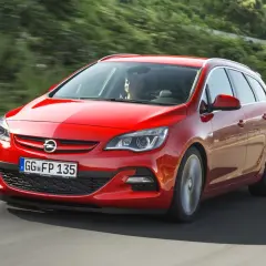 Czerwony Opel Astra J 1.4 Turbo 140 KM na drodze. Kierowca zadowolony, auto w ruchu.