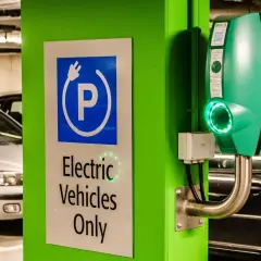 Zielona ładowarka EVbox i znak "Electric Vehicles Only" w garażu podziemnym. Zastanawiasz się, ile kosztuje ładowanie samochodu elektrycznego?