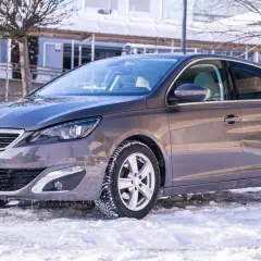 Szary Peugeot 308 na zimowych oponach, gotowy na śnieżne drogi. Wiele pozytywnych peugeot 308 opinie potwierdza jego wszechstronność.