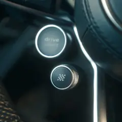 Przycisk z szachownicą na kierownicy, gotowy do aktywacji launch control. Obok przycisk Drive Select.