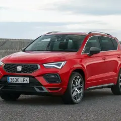 Czerwony Seat Ateca na tle kamiennego nabrzeża. Wiele osób szuka seat ateca opinie przed zakupem.