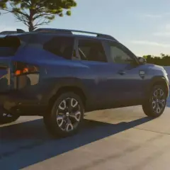 Niebieski Dacia Bigster na tle nieba i drzewa. Zbliżają się jego wymiary.