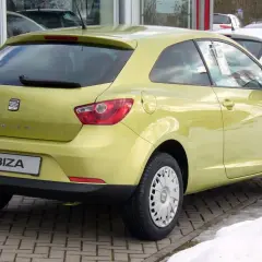 Żółty Seat Ibiza 1.4 benzyna z tyłu, zaparkowany na kostce brukowej.