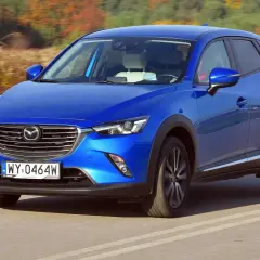 Niebieska Mazda CX-3 na drodze. Wiele pozytywnych mazda cx-3 opinie potwierdza jej stylowy wygląd i dynamikę jazdy.