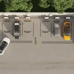 Widok z góry na parking z kilkoma samochodami, w tym żółtym i białym. Widać ładowarki do samochodów elektrycznych, sugerujące funkcję asystenta parkowania.