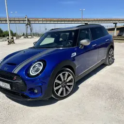 Niebieski Mini Cooper Clubman S z szarymi pasami na masce. Wiele osób chwali sobie jego zwinność i styl, co potwierdzają liczne mini cooper opinie.