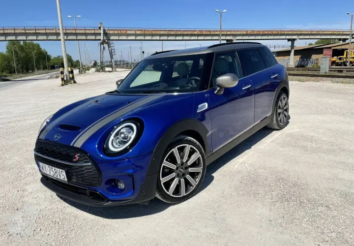 Niebieski Mini Cooper Clubman S z szarymi pasami na masce. Wiele osób chwali sobie jego zwinność i styl, co potwierdzają liczne mini cooper opinie.