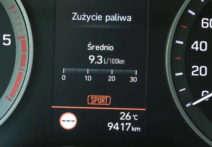 Na wyświetlaczu samochodu widać licznik spalania paliwa: średnie zużycie 9.3 L/100km. Obok widnieje tryb SPORT.