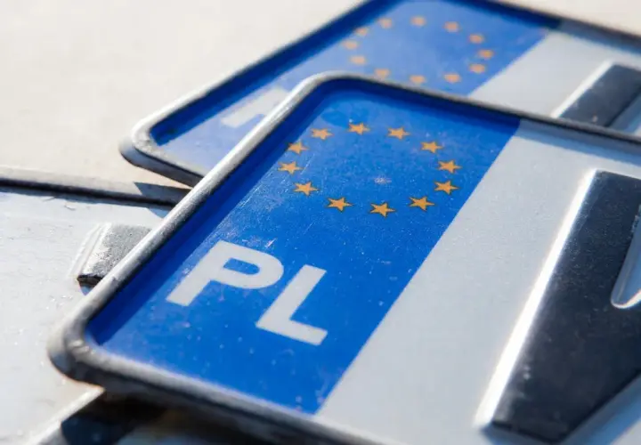 Zbliżenie na polskie tablice rejestracyjne z symbolem Unii Europejskiej. Widoczne litery "PL" i fragmenty numerów.