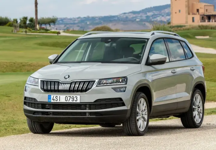 Szary Skoda Karoq na tle zielonych wzgórz. Wiele osób szuka skoda karoq opinie przed zakupem.