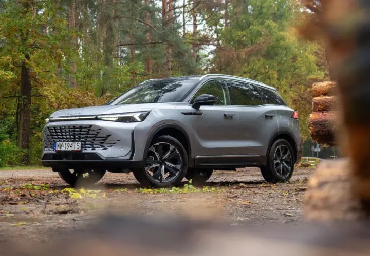 Srebrny SUV w lesie, gotowy na przygodę. Wiele pozytywnych baic 7 opinii potwierdza jego wszechstronność.