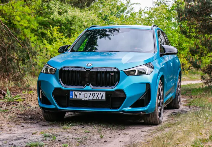 Niebieskie BMW X1 na leśnej drodze. Sprawdź jego kompaktowe bmw x1 wymiary, idealne do miasta i poza nim.