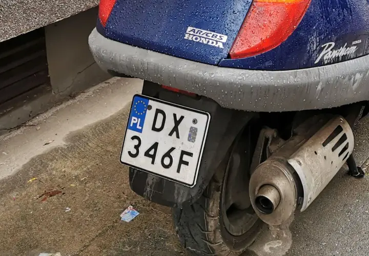 Skuter Honda Pantheon z tablicą rejestracyjną DX 346F, gotowy do jazdy po deszczu.