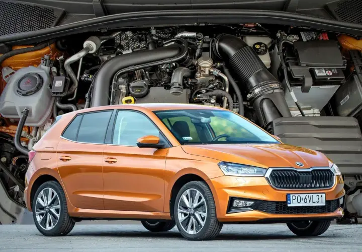 Pomarańczowa Skoda Fabia IV z widocznym silnikiem w tle.