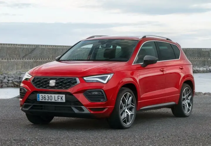 Czerwony Seat Ateca na tle kamiennego nabrzeża. Wiele osób szuka seat ateca opinie przed zakupem.