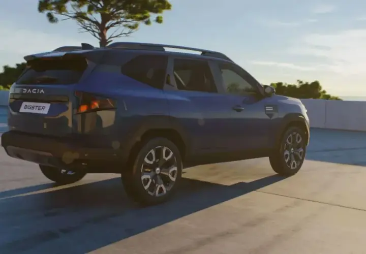 Niebieski Dacia Bigster na tle nieba i drzewa. Zbliżają się jego wymiary.