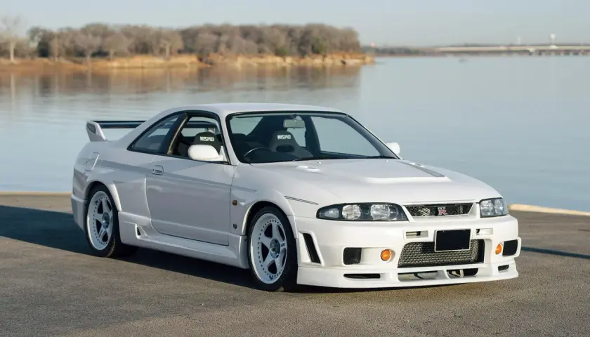 Białe r33 GT-R z siedzeniami Nismo stoi nad jeziorem.