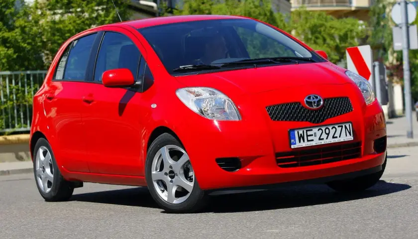 Czerwony Toyota Yaris 2009 z polskimi tablicami WE 2927N jedzie po ulicy.