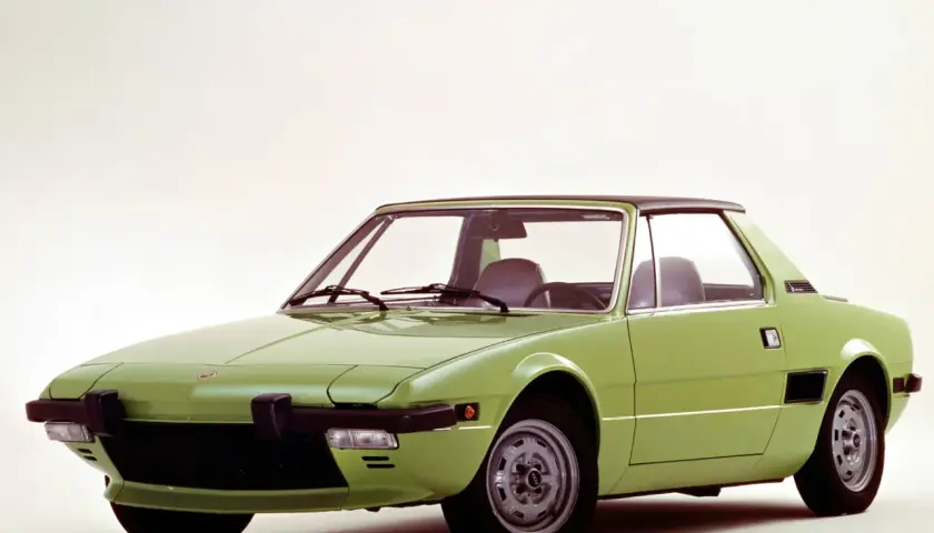 Zielony Fiat X1/9 z czarnym dachem, sportowy samochód z lat 70. na białym tle.