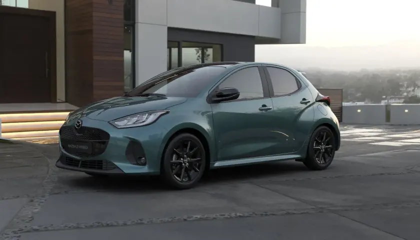 Elegancka, zielona Mazda 2 Hybrid stoi przed nowoczesnym domem.