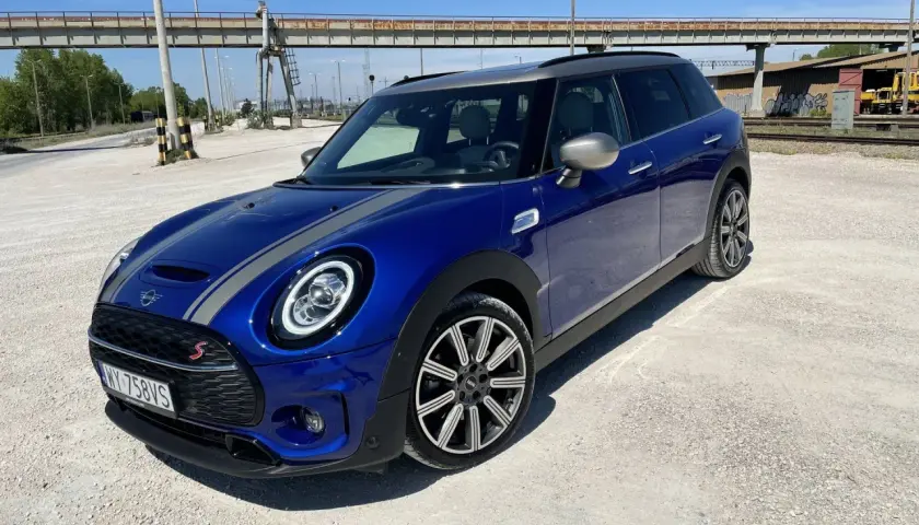 Niebieski Mini Cooper Clubman S z szarymi pasami na masce. Wiele osób chwali sobie jego zwinność i styl, co potwierdzają liczne mini cooper opinie.