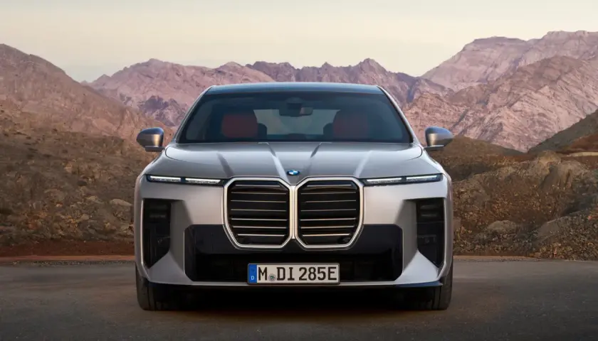 Przód luksusowego BMW 7 2025 z charakterystycznym grillem i nowoczesnymi światłami, zaparkowany na tle surowych górskich krajobrazów.