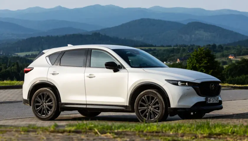 Biała Mazda CX-5 z czarnymi felgami na tle górskiego krajobrazu. KSU rejestracja widoczna na tablicy.