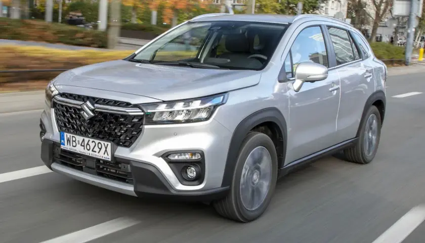 Srebrny Suzuki S-Cross w ruchu miejskim. Wiele osób szuka **Suzuki S-Cross opinie** przed zakupem.
