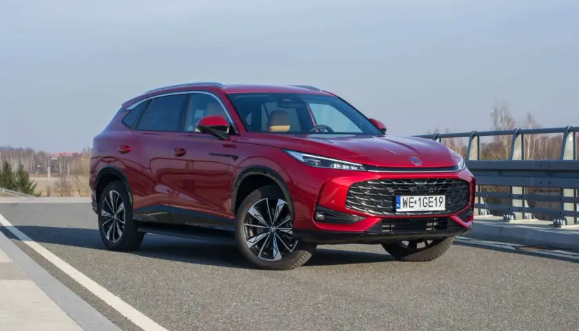 Czerwony MG HS Hybrid na drodze, z widocznym grillem i światłami LED. Elegancki SUV gotowy na podróż.