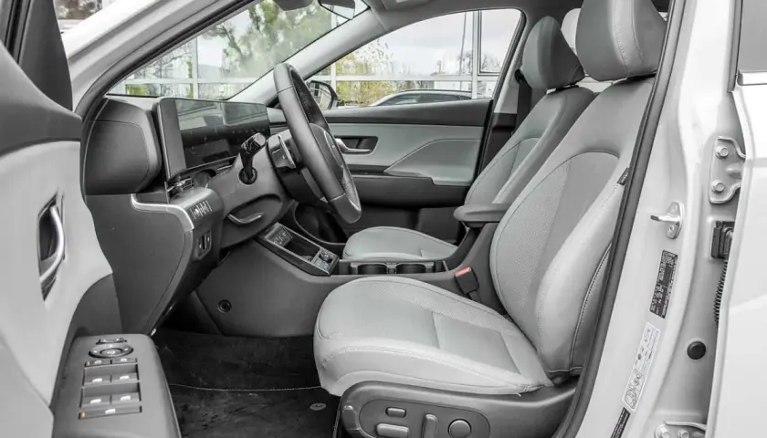 Wnętrze Hyundai Kona Hybrid z jasnoszarymi skórzanymi fotelami, nowoczesnym panelem sterowania i dużym ekranem multimedialnym.