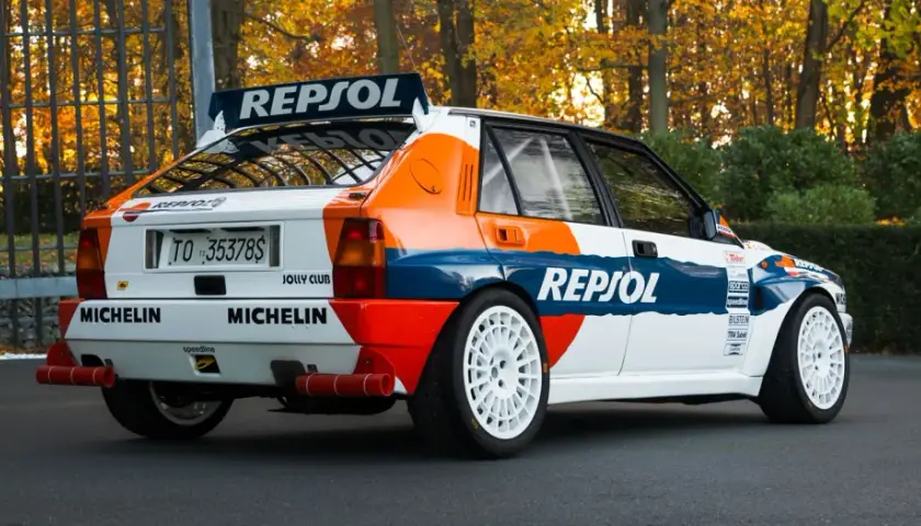 Ikoniczna Lancia Delta Integrale w barwach Repsol, z białymi felgami i naklejkami Michelin, gotowa do rajdu.