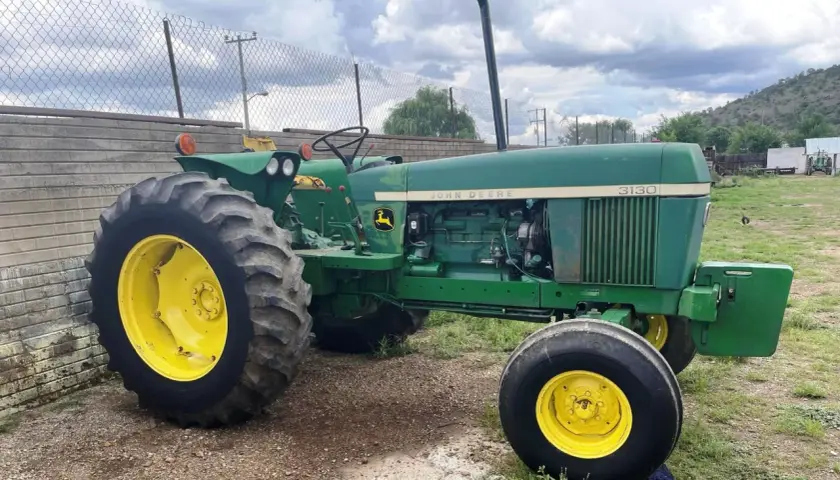 Zielony John Deere 3130 z żółtymi felgami, gotowy do pracy na polu.