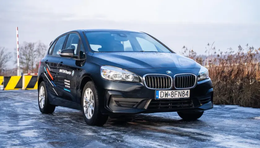 Czarny BMW 2 Active Tourer na oblodzonej drodze, gotowy na zimowe wyzwania.