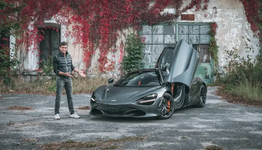 Mężczyzna prezentuje szarego McLarena 720S z otwartymi drzwiami. Zastanawiasz się nad mclaren 720s cena?