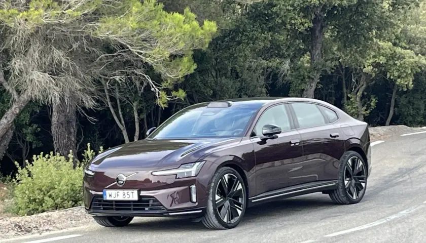 Elegancki, ciemnobrązowy Volvo ES90 na krętej drodze wśród zieleni.