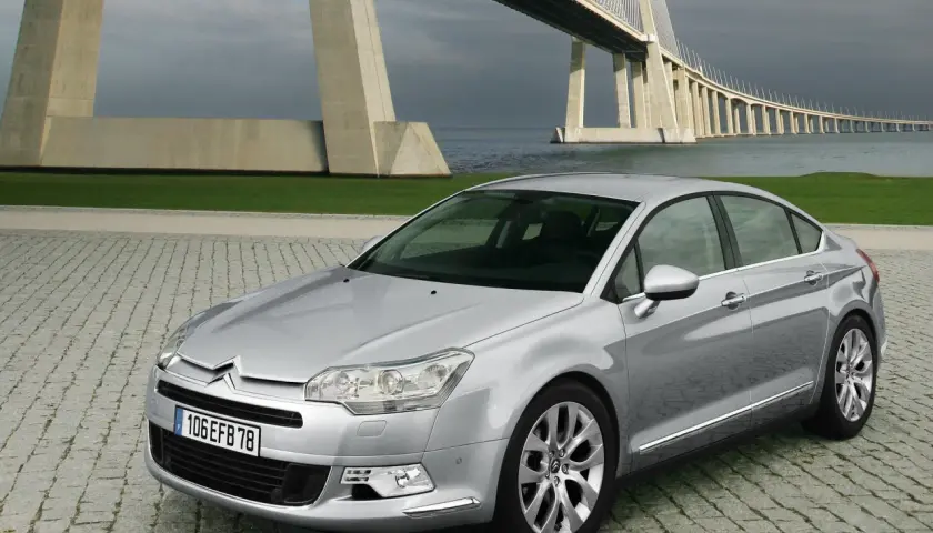 Srebrny Citroen C5 2.0 HDI na tle imponującego mostu wiszącego.